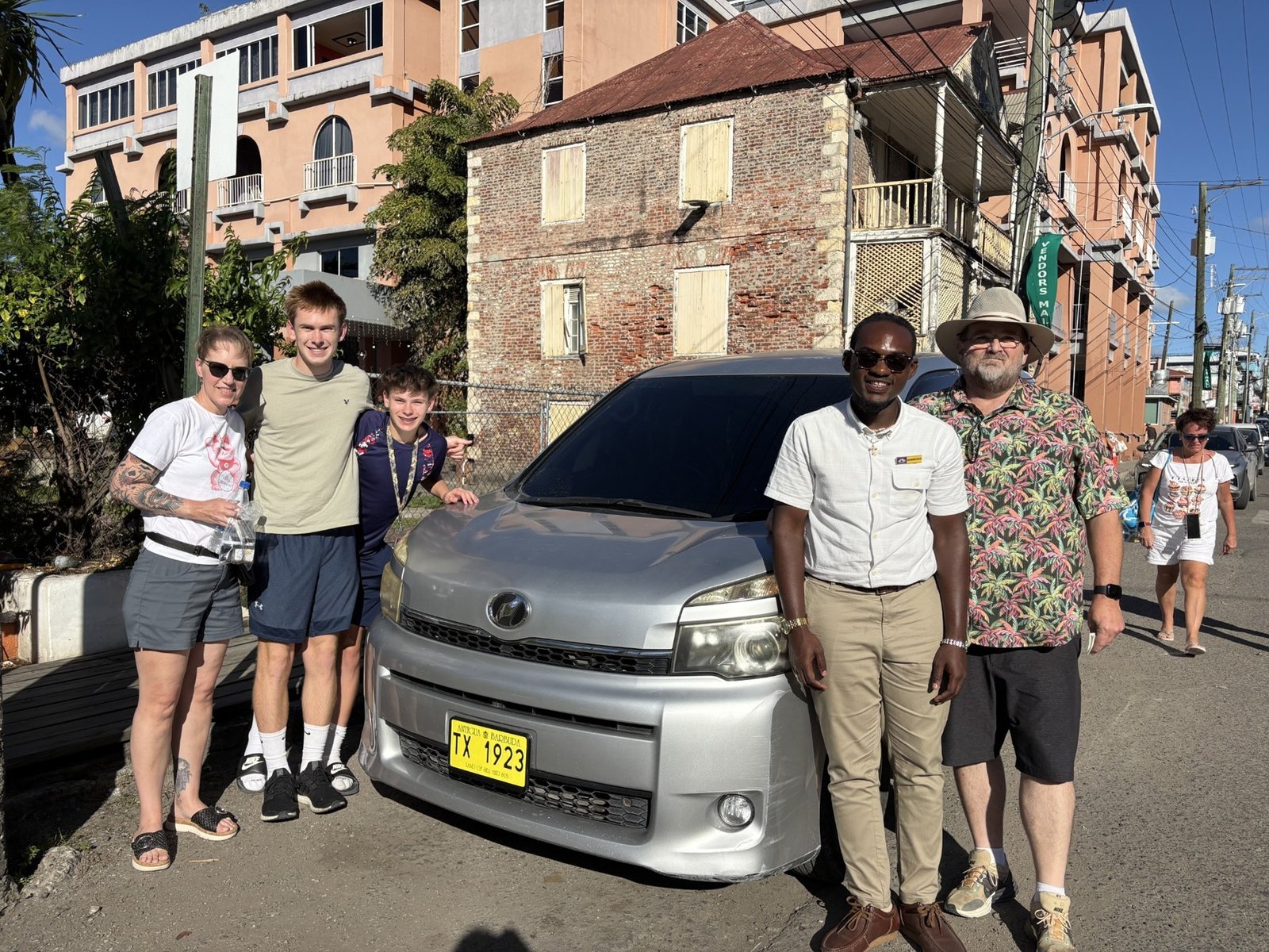 Driver and guests beside the taxi on a town street.