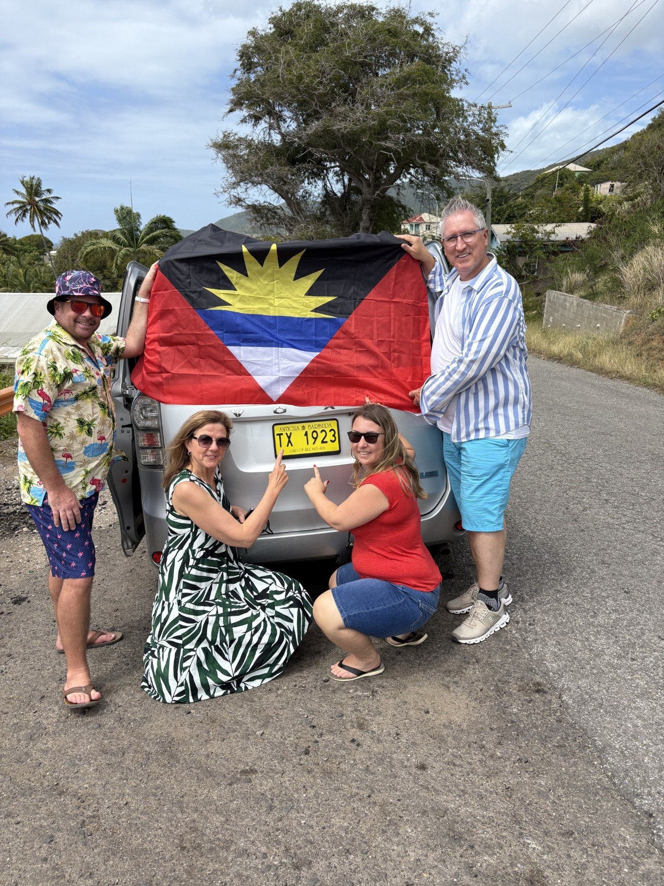Guests with a large Antigua and Barbuda flag beside the taxi.