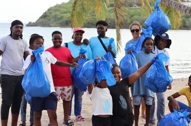 Group photograph with blue bags from a coastal clean-up.