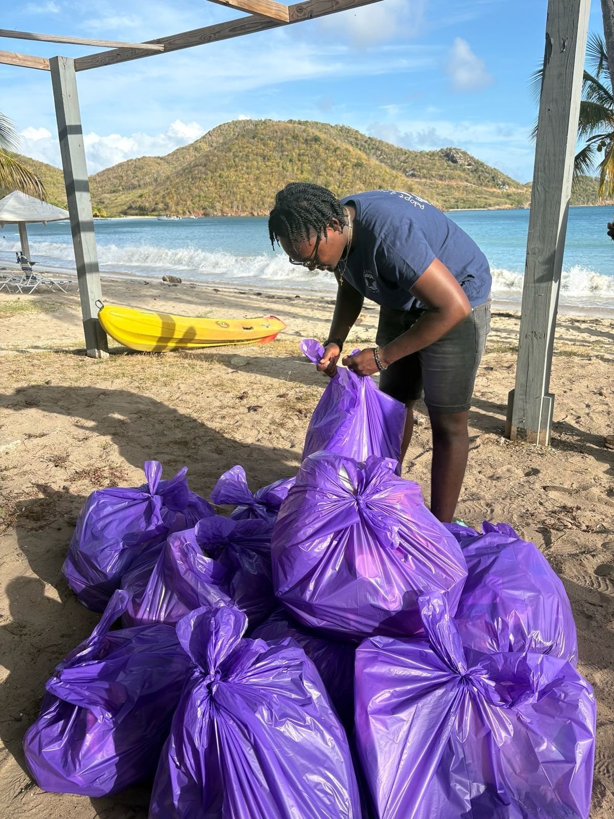 Coastal clean-up participant tying purple waste bags.