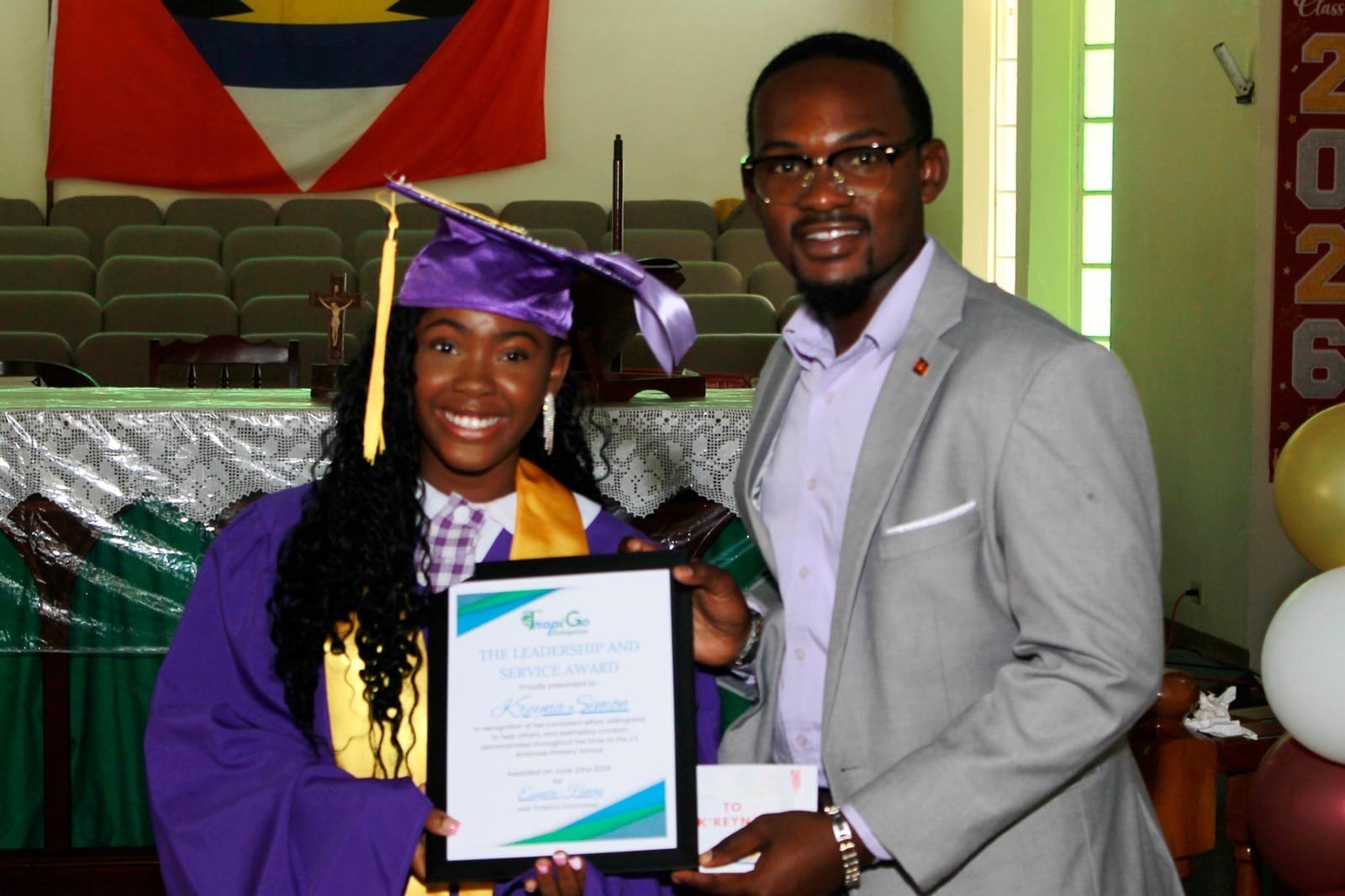 A graduate receiving a framed TropiGo award.